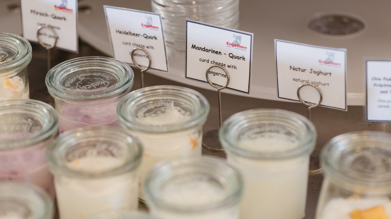 Weckgläser mit hausgemachtem Quark am Frühstücksbuffet, beschriftet mit Pfirsich, Heidelbeer, Mandarine und Naturjoghurt